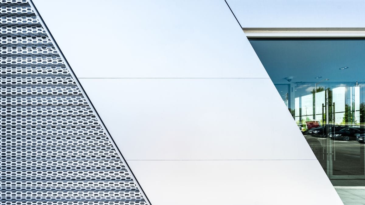 The sloped glass roofline of a modern building above a paved plaza
