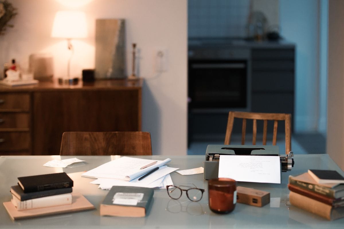 A bright desk with a typewriter, papers, glasses and a coffee cup